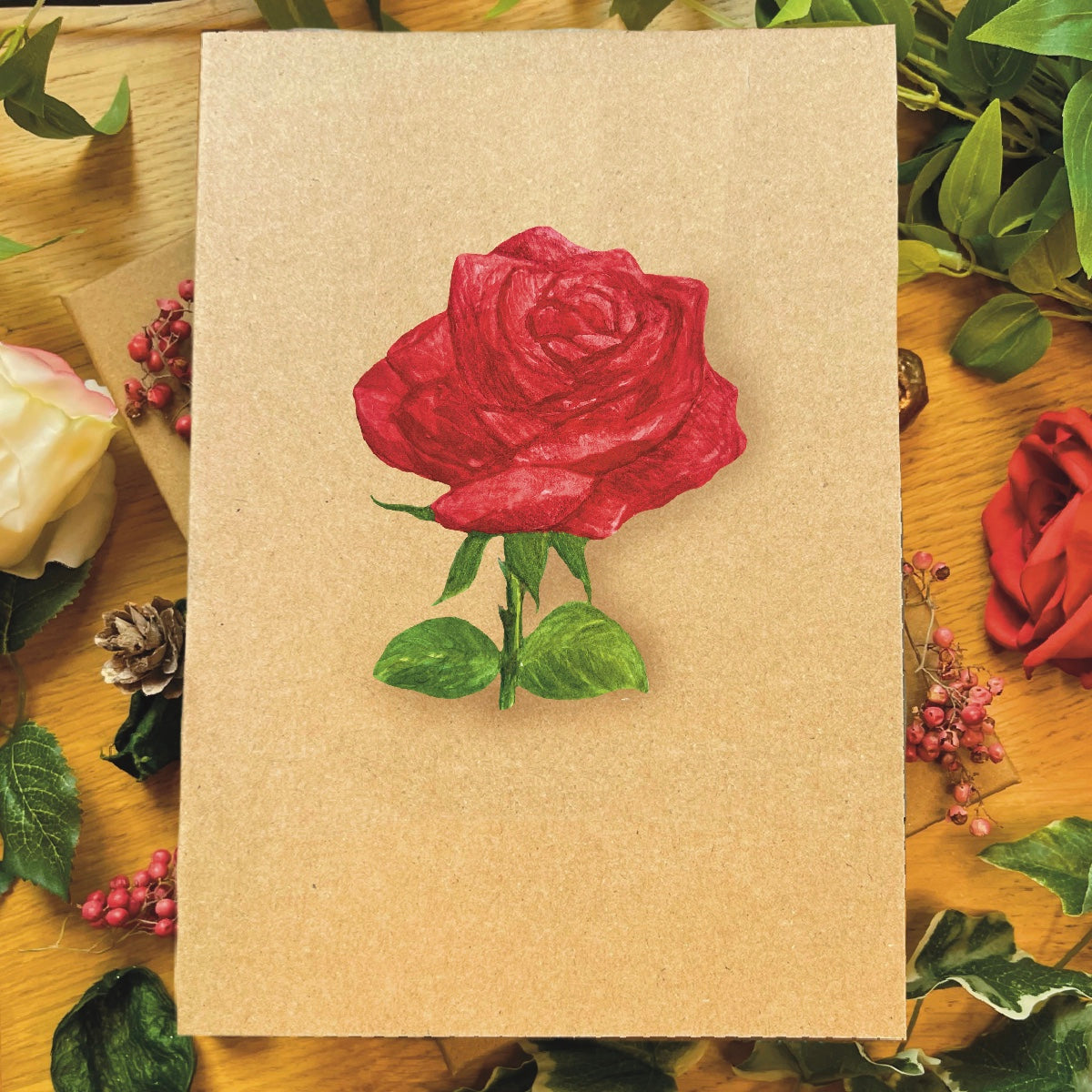 Greetings card in recycled brown manila featuring a watercolour red rose in bloom