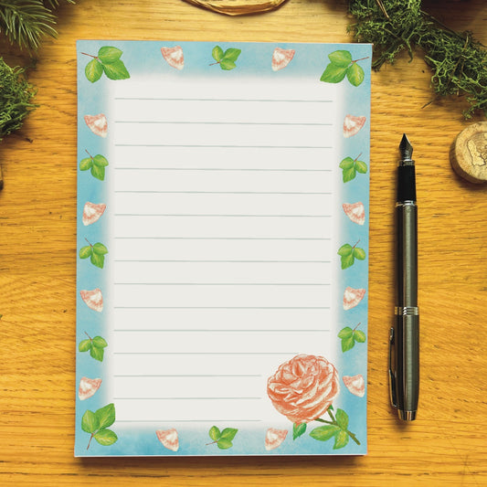Peach rose illustrated notepad with sky blue border decorated with peach petals and leaves