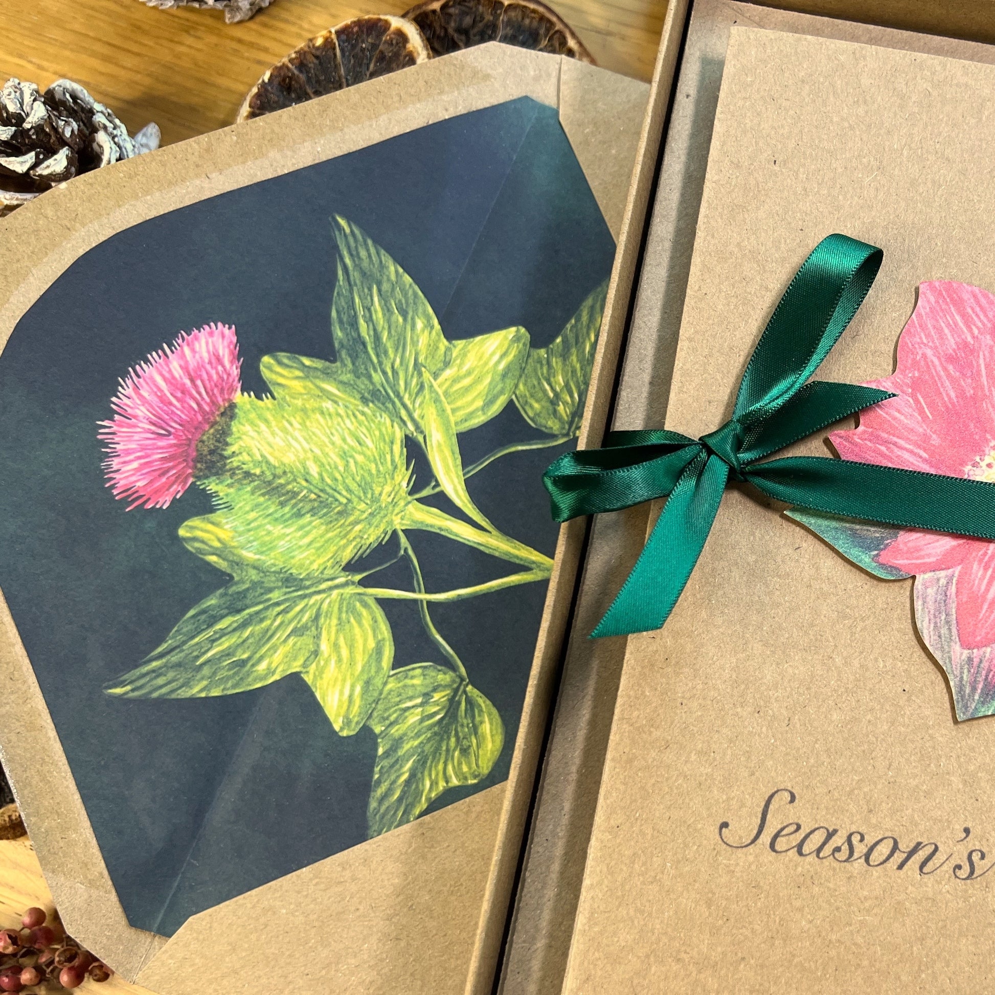 Thistle and ivy illustrated inlay on a Manila envelope next to a box of greetings cards