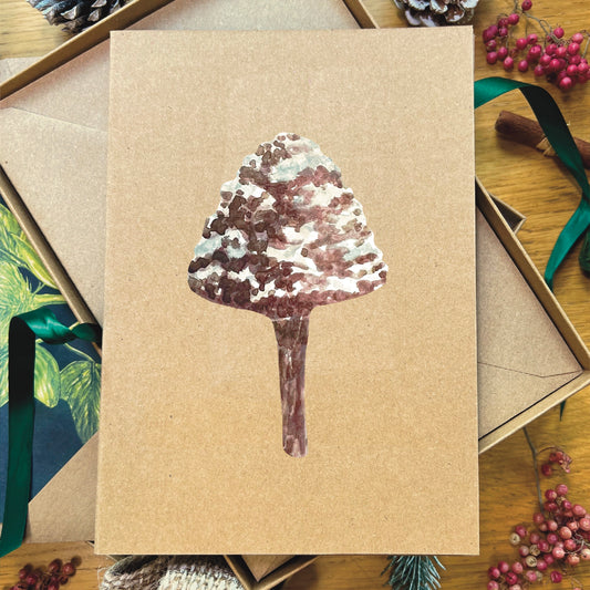 Snow topped mottlegill mushroom illustrated in watercolour attached to Manila recycled greetings card on a wooden desk