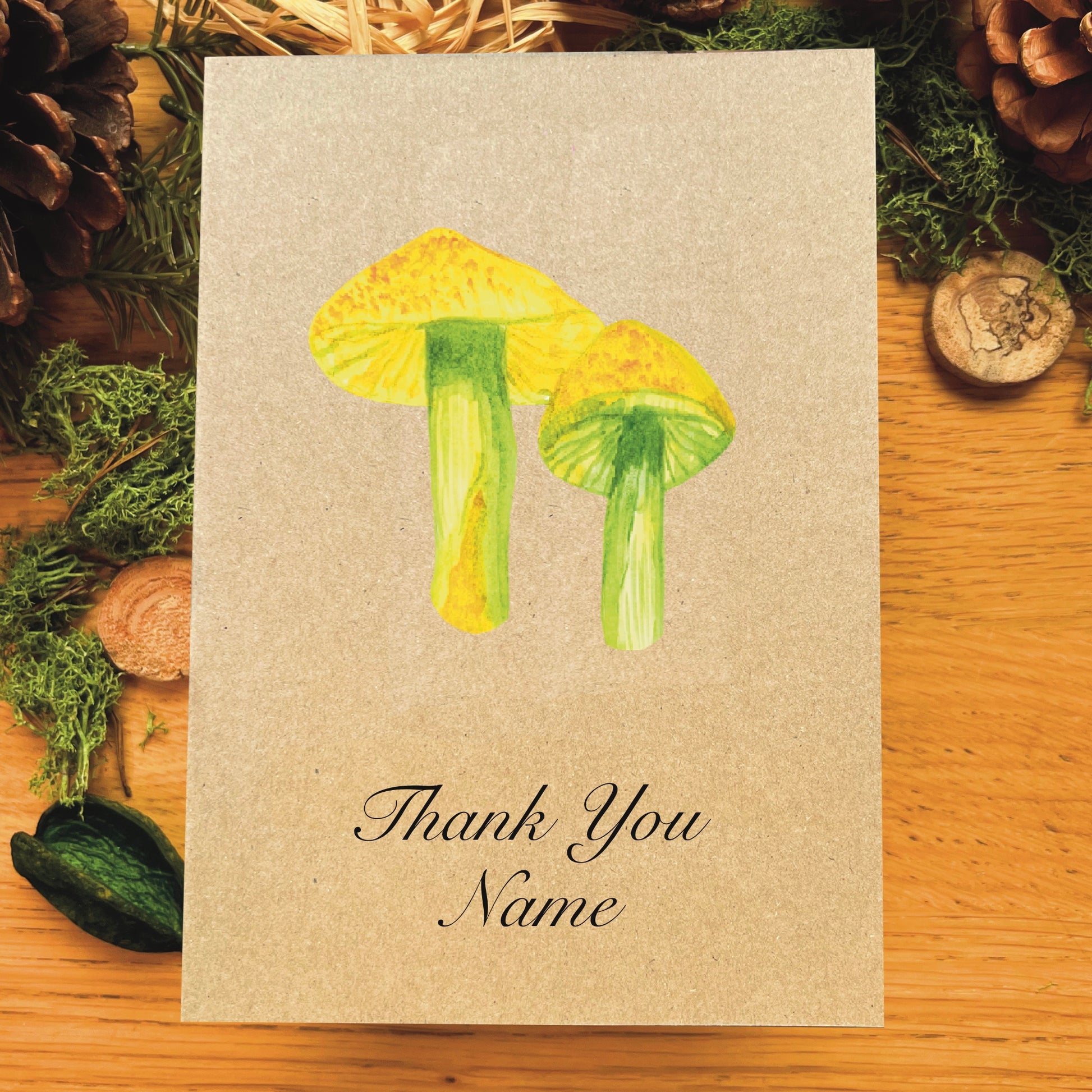 Parrot waxcap illustrated in watercolour attached to Manila recycled greetings card on a wooden desk, with text script Thank You Name underneath the illustration