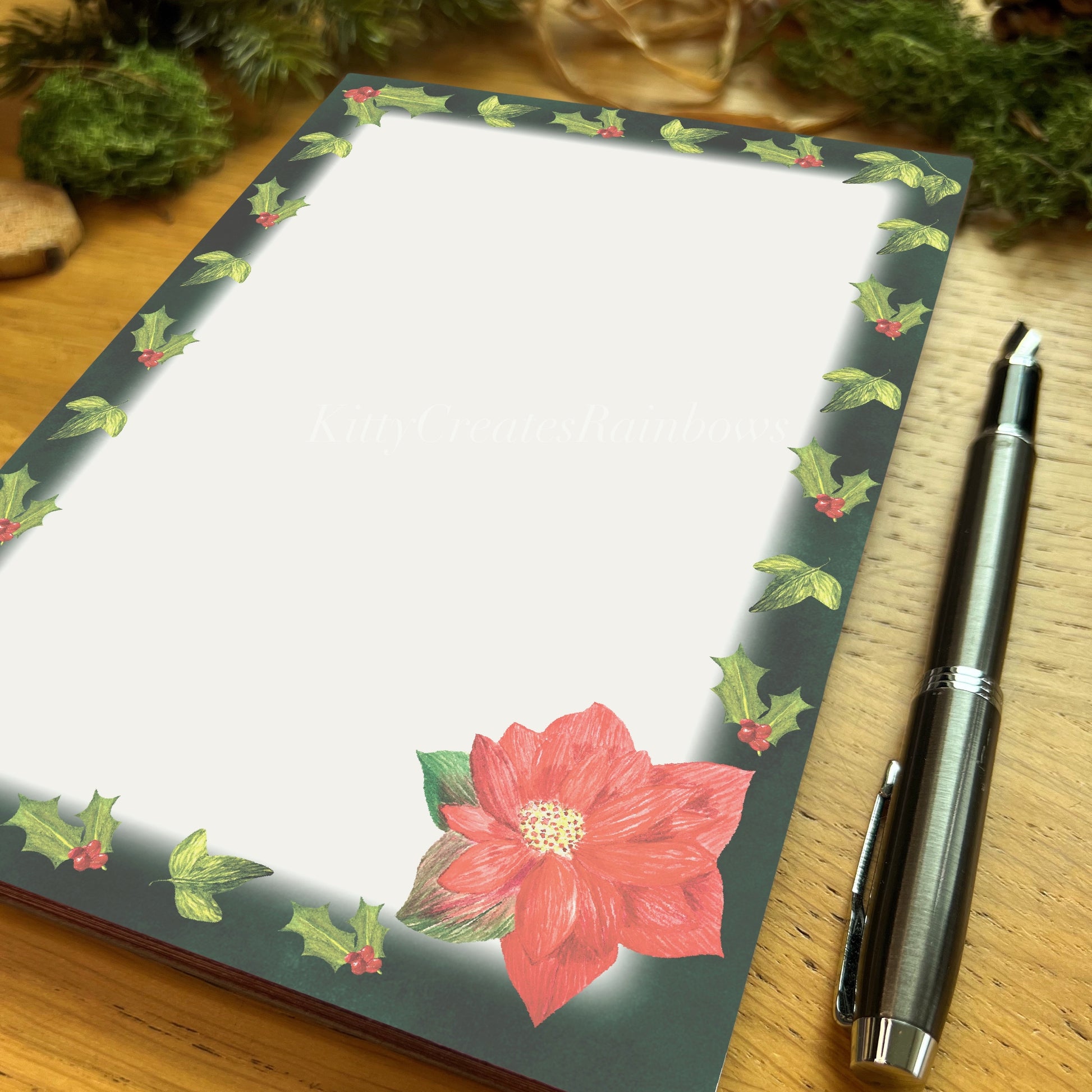 Winters bloom red poinsettia illustrated notepad with dark evergreen border, on a wooden table with fountain pen