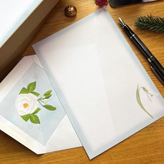 White winter floral illustrated paper and envelope with illustrated inlay, on a wooden desk