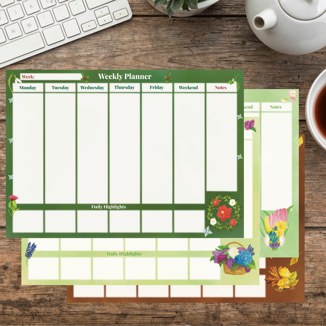 4 weekly planner pads stacked on a wooden desk all illustrated with vibrant botanicals